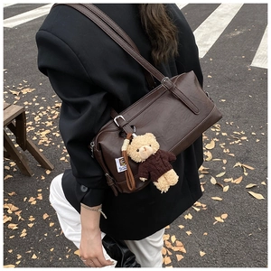 Outdoor street style view of brown vintage shoulder bag with cute teddy bear charm