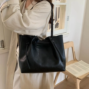 Close-up of minimalist black PU leather tote bag with unique drawstring and slim handles