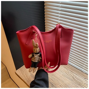 Détail du sac cabas en cuir rouge avec lettrage doré et charm lapin en peluche