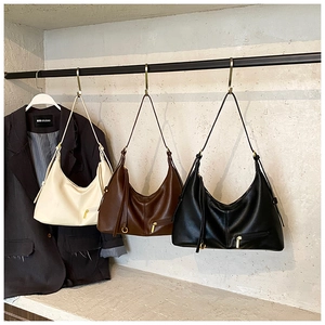 Minimalist tote bags in cream, brown, and black colors hanging on a metal display rack