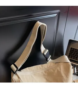 Detail of adjustable wide nylon shoulder strap and buckle on the beige crossbody bag