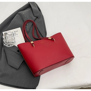 Detail shot of a luxury red leather tote bag with elegant golden hardware and slim handles