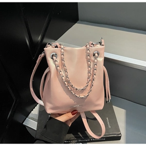 Detail of pink leather bucket bag showing silver chain handle and matte texture
