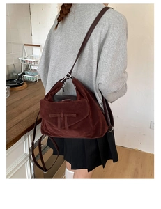 Detail of dark red suede vintage shoulder bag with leather strap shown in a lifestyle setting