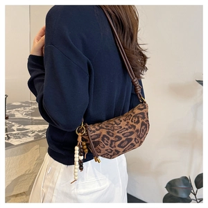 Detail of leopard print crescent bag with colorful bead charm and leather shoulder strap