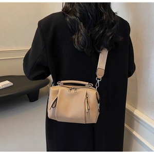 Detail of khaki pebbled leather crossbody bag with dual zippers and wide shoulder strap