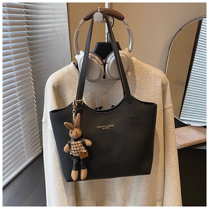 Détail du sac fourre-tout noir rétro en cuir avec texture litchi et breloque lapin mignonne