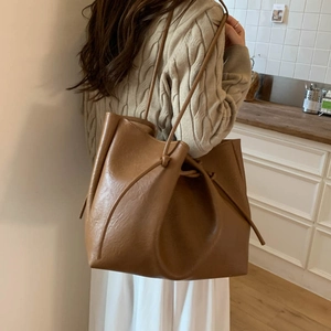Detail of camel PU leather tote showing knotted shoulder straps and soft texture