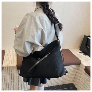 Close-up of black quilted hobo bag with adjustable eyelet strap on a female model