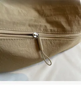 Detailed macro view of khaki nylon fabric texture and smooth zipper on a shoulder bag