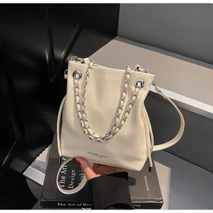 Detail of cream white bucket bag with silver chain handle and drawstring closure
