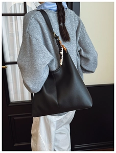 Detail of black pebbled leather hobo bag featuring decorative beads on shoulder strap