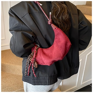 Détail du sac croissant en daim rouge montrant le design en forme de corne et le nœud bandoulière