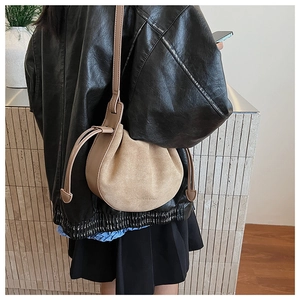 Detail der beigen Wildleder-Eimertasche mit Kordelzug und aufgedrucktem Mode-Slogan