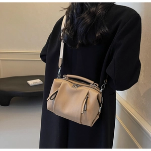 Detail view of khaki pebbled leather Boston bag with silver hardware and wide shoulder strap