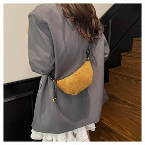Detail of suede crossbody bag with braided rope strap and golden metal hardware