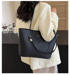 Close-up of a large black leather tote bag with gold lettering and white stitching