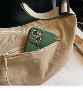 Detail of the front zipper pocket on a beige nylon moon bag holding a large smartphone