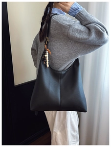 Detail of black lychee grain leather hobo bag featuring decorative wooden bead charm