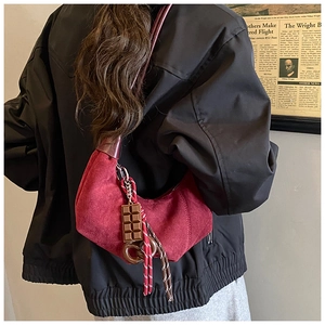 Détail du sac hobo en daim rouge avec breloque chocolat et corde tressée sur modèle