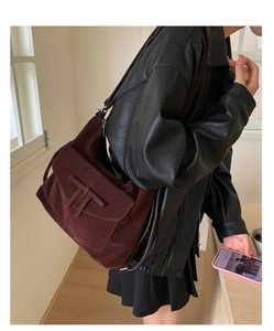 Detail of burgundy suede shoulder bag featuring retro flap closure and leather T-bar accents