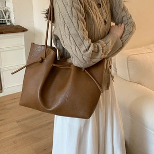 Detail of the vintage brown tote bag featuring a stylish side drawstring knot and leather texture