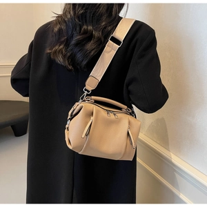Detail of light beige boston bag with silver dual zippers and wide woven shoulder strap
