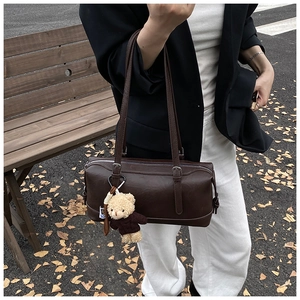Detail of vintage coffee brown Boston barrel bag with soft matte texture and bear charm
