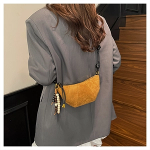 Detail of ginger suede crescent bag with wooden bead charm and knotted shoulder strap