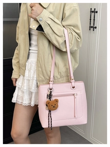 Detail of pink pebbled leather tote bag with zip pocket and cute brown teddy bear charm