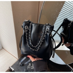 Detail of black leather bucket bag with silver chain strap and drawstring closure