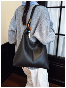 Detailed macro of black lychee grain leather tote with ethnic style wooden bead pendant