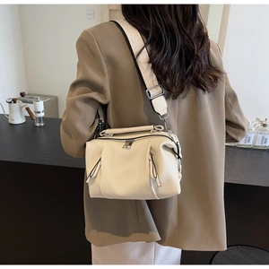 Detail of cream lychee leather pillow bag with wide strap and silver hardware on a model