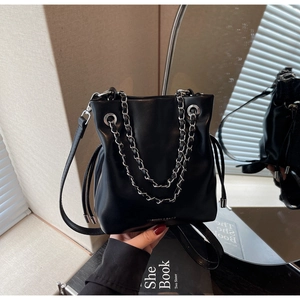 Close-up of black leather bucket bag featuring silver chain handle and fashion text logo
