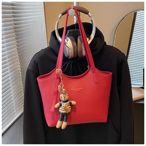 Détail d'un sac cabas rouge en similicuir avec un pendentif lapin et des lettres de mode