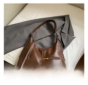 Detailed view of brown lychee grain leather hobo bag with fringe and gold zip pocket