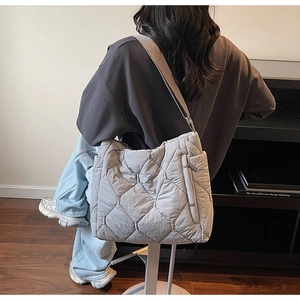 Detail view of light grey quilted tote bag with hexagon pattern and wide shoulder strap