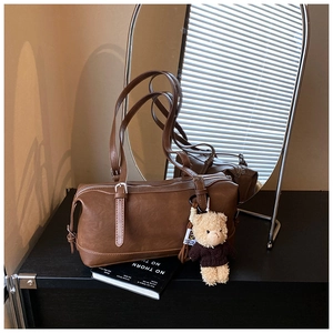Detailed close-up of brown vintage shoulder bag with bear pendant and matte texture