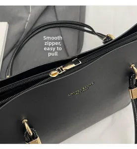 Detail view of the smooth gold-tone zipper and logo branding on a black leather tote bag