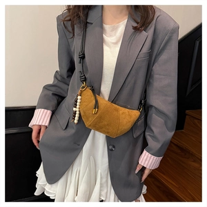 Brown suede crescent bag featuring black braided strap and colorful beaded tassel detail