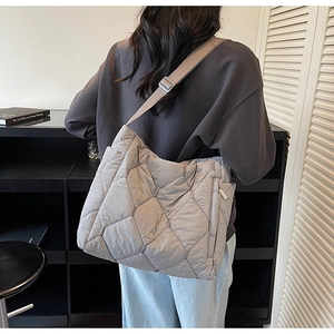 Detailed back view of a grey quilted puffer crossbody bag with an adjustable wide strap