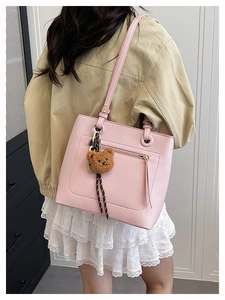 Detail view of large pink pebbled leather tote bag with a cute brown plush bear charm accessory