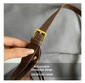 Detail of adjustable leather shoulder strap with gold metal buckle on a brown tote bag