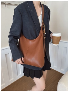 Detailed macro view of caramel brown pebbled leather texture on a large hobo shoulder bag