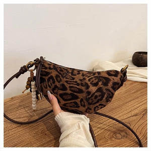 Detailed view of leopard print crescent bag with leather strap and beaded tassel charm