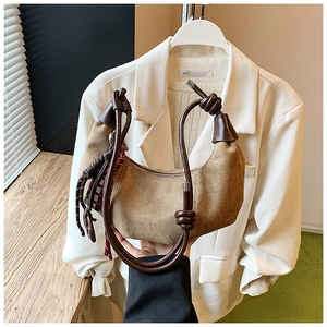 Détail d'un sac demi-lune en faux daim marron avec bandoulière nouée et gland à franges