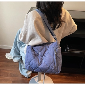 Detail of purple quilted puffer tote bag with side zipper pocket and shoulder strap