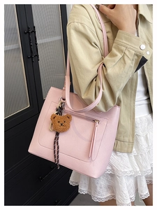 Close-up of pink leather tote bag featuring lychee texture and cute bear charm accessory