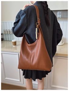Detail of a brown textured faux leather tote bag with unique wooden bead charm detail