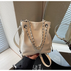 Detail of cream drawstring bucket bag with silver chain strap and leather shoulder strap